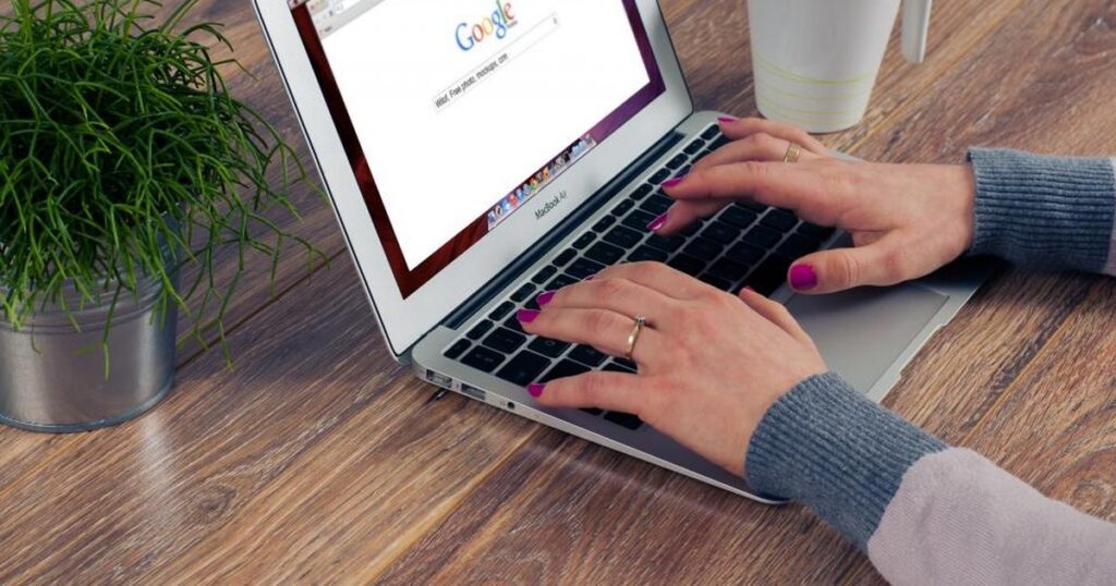 Handen typen op een laptop met de zoekpagina van Google geopend